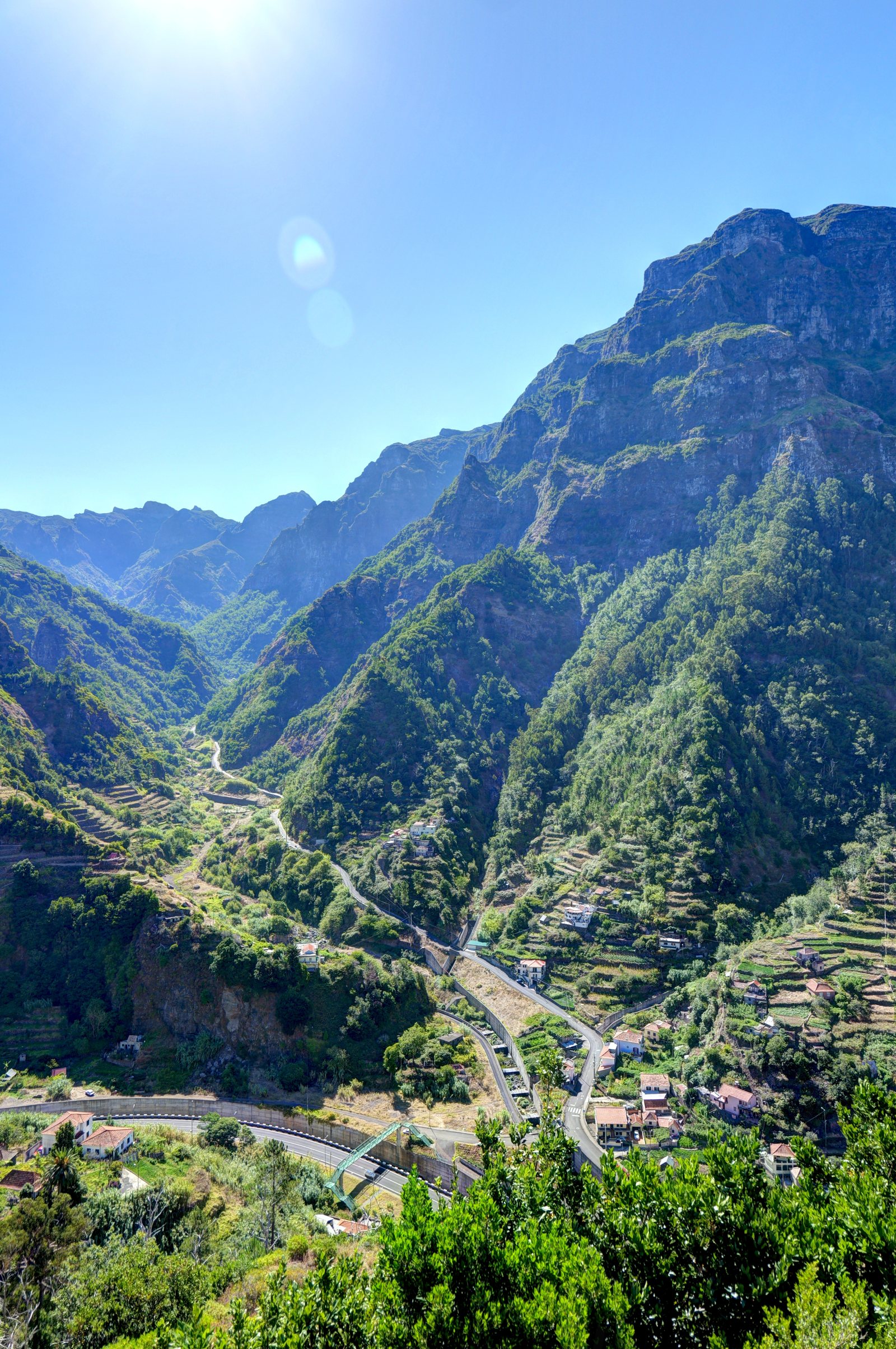 Valle montuosa con case sparse e strade fra colline verdi