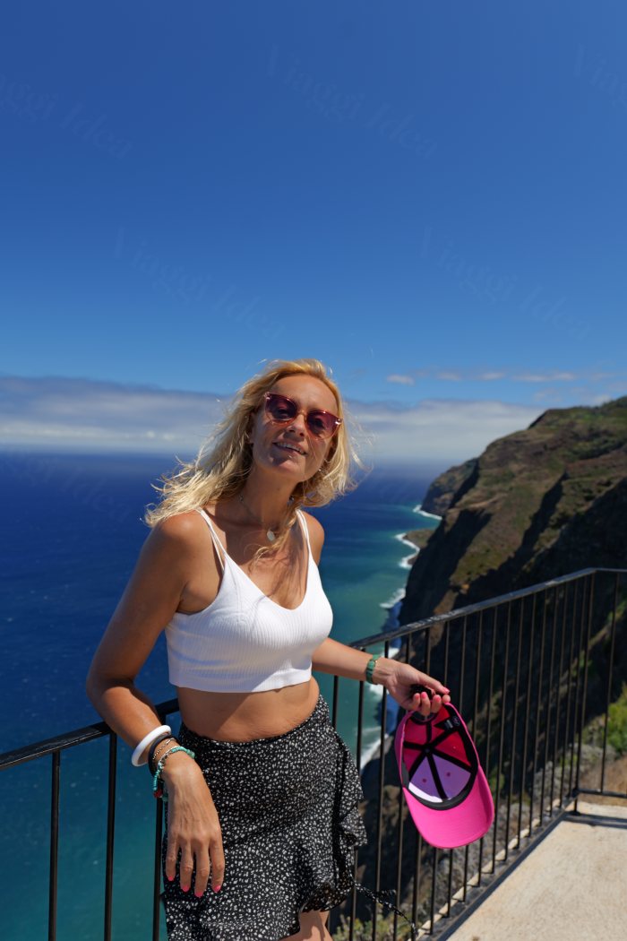 Donna sorridente su una balconata con vista sul mare e sulle scogliere